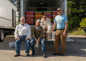 Great Lakes Bee Company volunteers pose in front of cases of bees on a truck